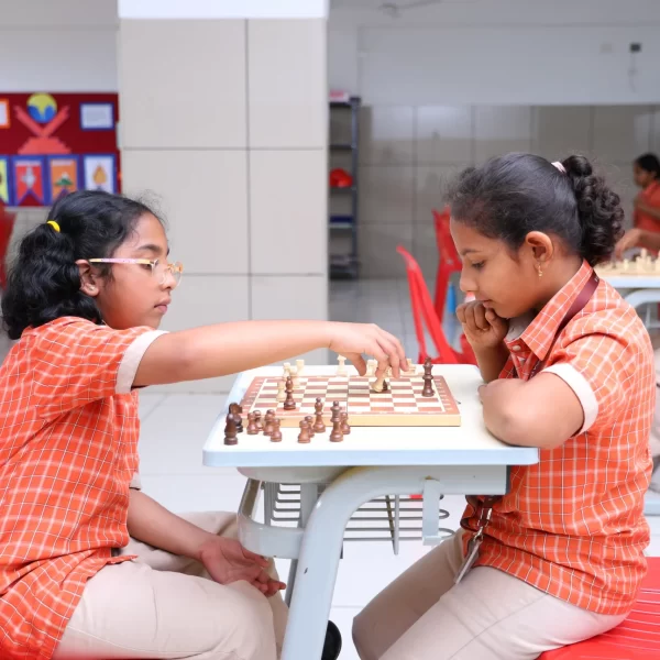Two schoolchildren playing chess in a classroom.