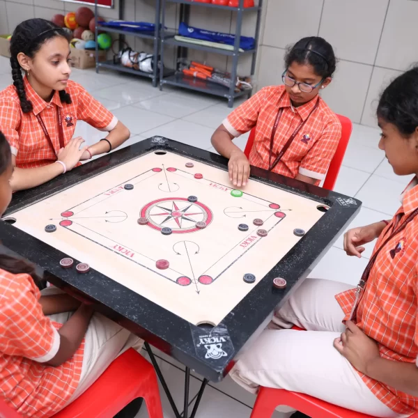 Four schoolchildren playing carrom at a table.