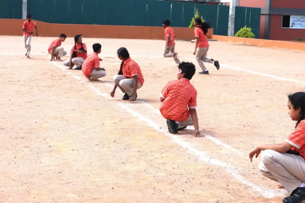 Students sitting and preparing on a playground field during an outdoor activity.