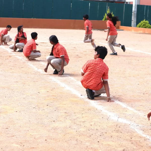 Students sitting and preparing on a playground field during an outdoor activity.