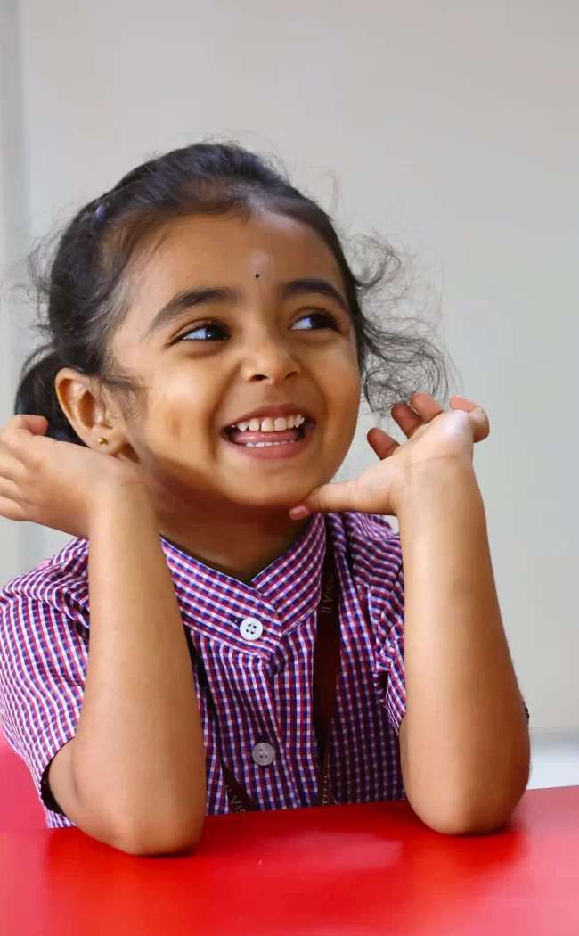 A young child smiling while sitting at a table.