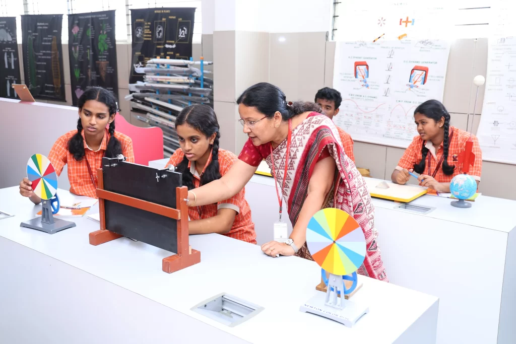 Students in a classroom setting conducting experiments with equipment, guided by a teacher, with educational models and charts in the background.