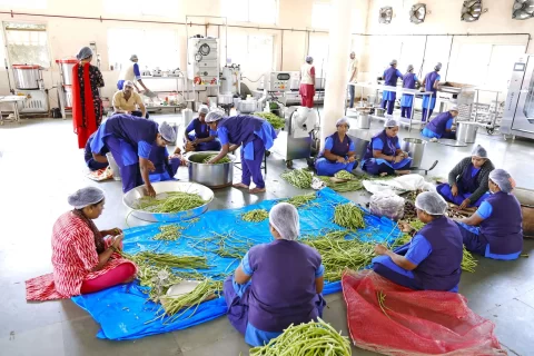 Staff working in the in-house kitchen at Vishwa Vidyapeeth, preparing vegetables in a spacious and organized setting.