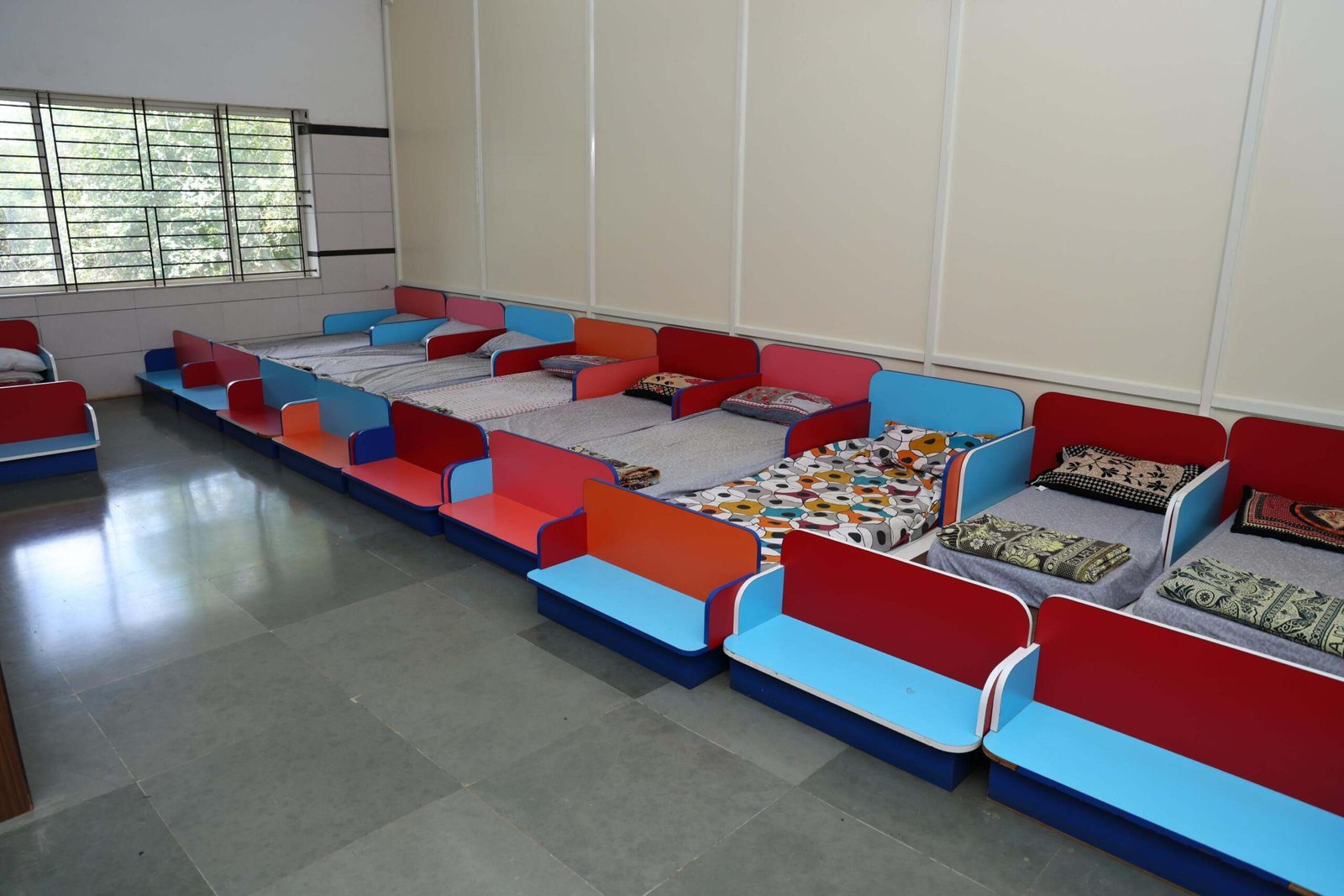 Children's sleeping area with low beds, colorful headboards, and neatly arranged bedding.