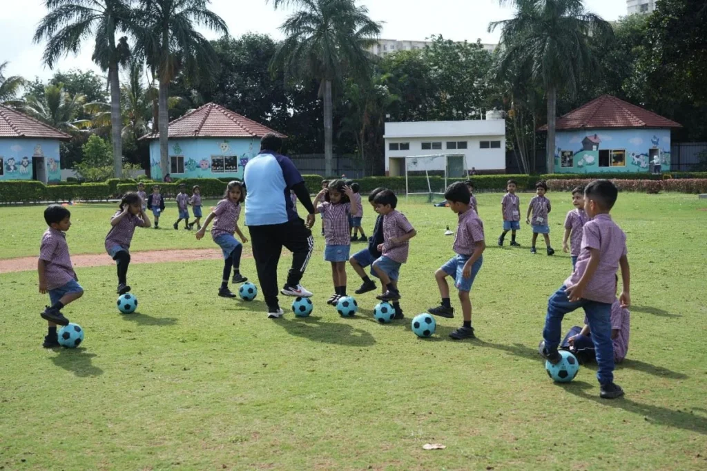 Young school children playing together on a lush green outdoor lawn, enjoying fun activities and physical recreation at the school campus.