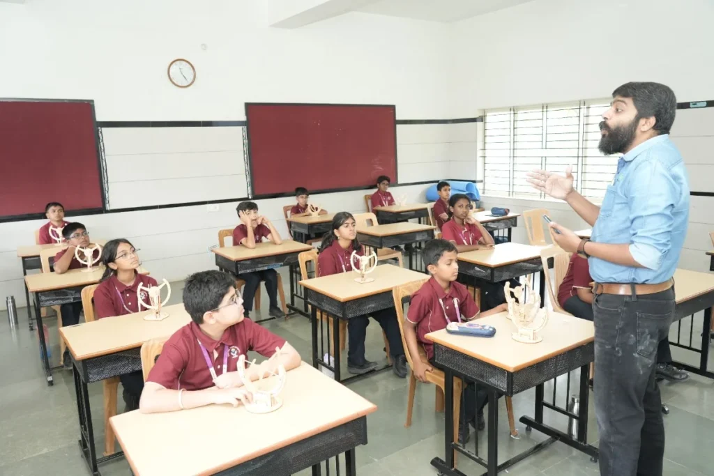 Teacher guiding students during a classroom lesson at Vishwavidyapeeth School in Bangalore.
